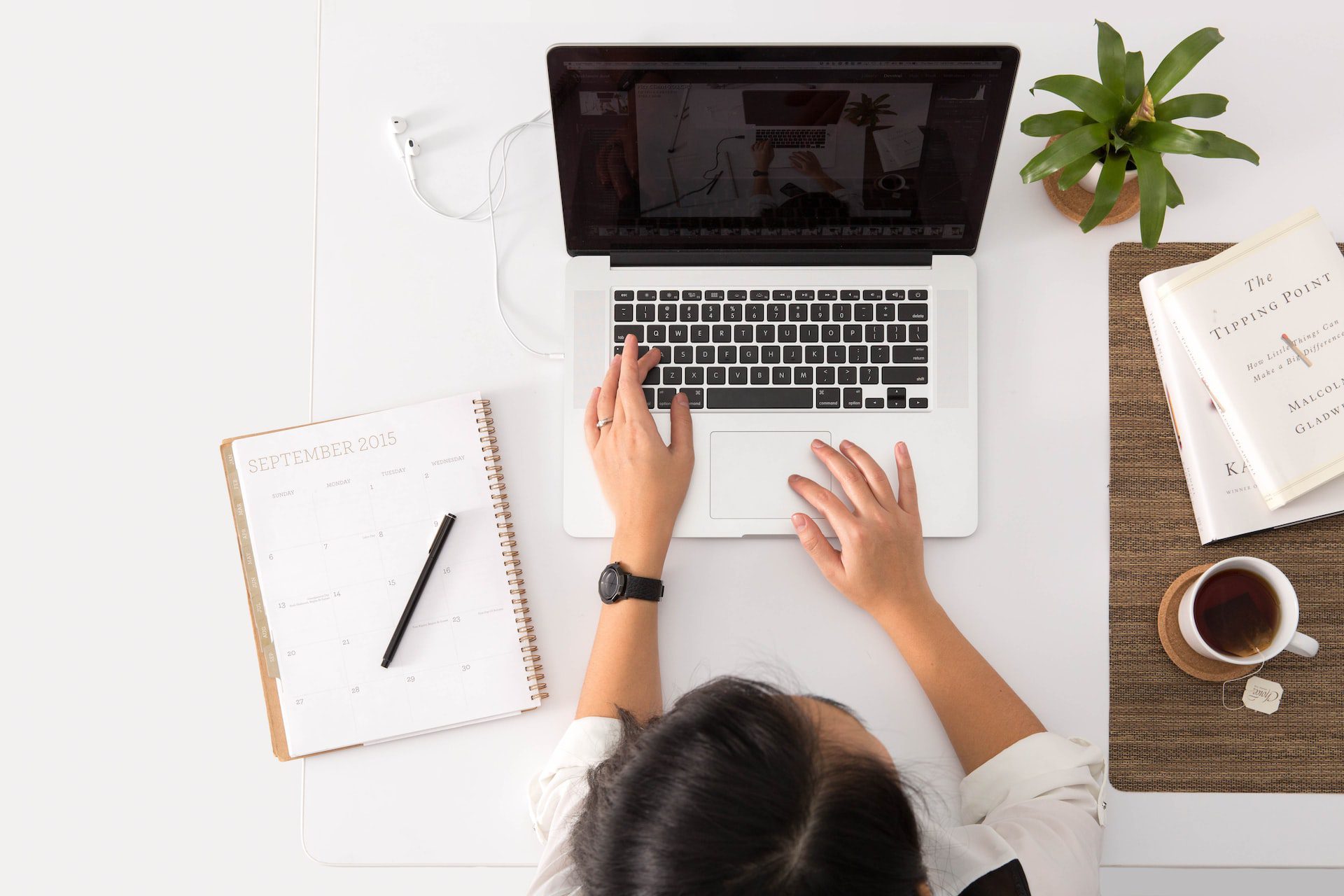 woman working on laptop with notebook beside it